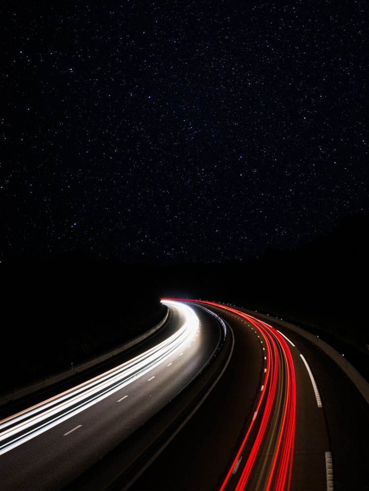 Trainées de lumière de phares de voiture sous un ciel étoilé | Light trails from cars under a starry sky