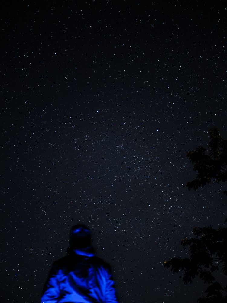 Homme éclairé en bleu sous un ciel étoilé | Man backlit in blu under a starry sky